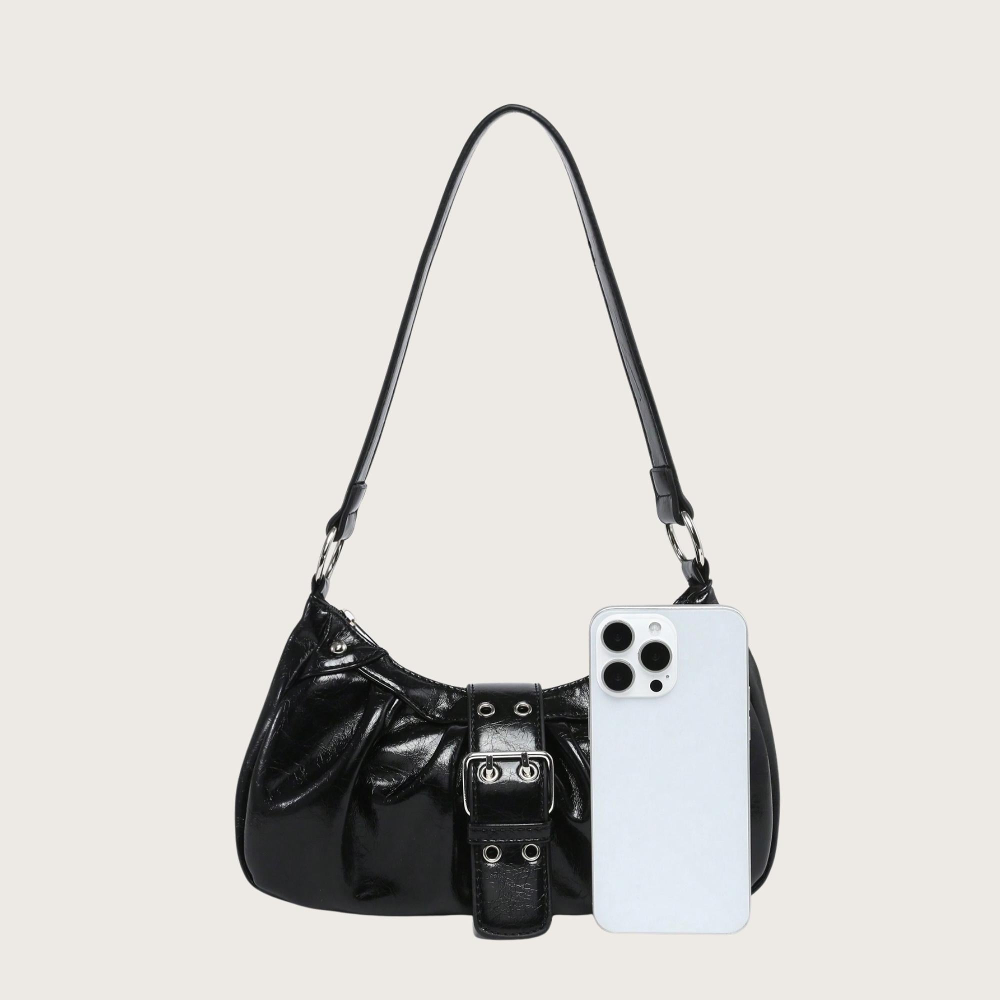 Black handbag with a phone for scale on a light gray background